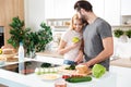 Smiling young loving couple standing at kitchen and cooking Royalty Free Stock Photo