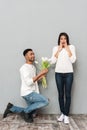 Smiling young loving couple standing over grey wall. Royalty Free Stock Photo