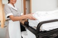 Smiling young maid taking fresh towels from a housekeeping cart Royalty Free Stock Photo