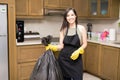 Happy young housewife holding disposal bag with trash Royalty Free Stock Photo