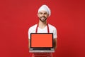 Smiling young male chef cook or baker man in striped apron t-shirt toque chefs hat isolated on red background. Cooking Royalty Free Stock Photo