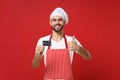 Smiling young male chef cook or baker man in striped apron white t-shirt toque chefs hat isolated on red background Royalty Free Stock Photo