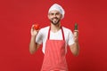 Smiling young male chef cook or baker man in striped apron white t-shirt toque chefs hat isolated on red background Royalty Free Stock Photo