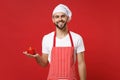 Smiling young male chef cook or baker man in striped apron white t-shirt toque chefs hat isolated on red wall background Royalty Free Stock Photo