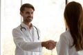 Smiling male doctor handshake female client greeting in clinic