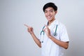 Smiling Young male Doctor wears uniform with tethoscope, pointing a copy space Royalty Free Stock Photo