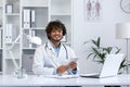 Smiling young male doctor in white coat working at modern medical office desk Royalty Free Stock Photo