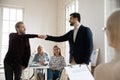 Smiling young male employee bumping fists with colleague in office.