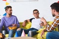 smiling young male friends drinking beer and eating snacks at home