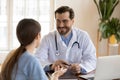 Smiling young male general practitioner in uniform listening to woman.