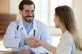 Smiling young male gp doctor shaking hands with patient. Royalty Free Stock Photo