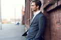 Smiling young male manager formal dressed leaning on a wall outdoors. Royalty Free Stock Photo