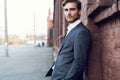 Smiling young male manager formal dressed leaning on a wall outdoors. Royalty Free Stock Photo