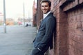 Smiling young male manager formal dressed leaning on a wall outdoors. Royalty Free Stock Photo