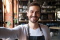 Smiling young waiter wear apron take selfie looking at camera Royalty Free Stock Photo