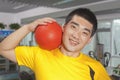 Smiling young man with ball on his shoulder in the gym Royalty Free Stock Photo
