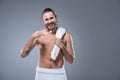 Smiling young man with bath towel on shoulder holding toothbrush with toothpaste in hand, Royalty Free Stock Photo