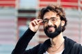 Smiling young man with beard putting on glasses Royalty Free Stock Photo