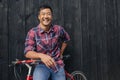 Smiling young man with a bike against a city wall Royalty Free Stock Photo