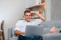 Smiling young man browsing Internet while lying on the couch. Royalty Free Stock Photo