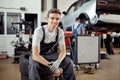 A smiling young man is at a car sevice during a break