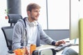 Smiling young man in casual clothing using computer, streaming playthrough or walkthrough video Royalty Free Stock Photo