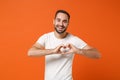 Smiling young man in casual white t-shirt posing isolated on orange wall background, studio portrait. People lifestyle Royalty Free Stock Photo