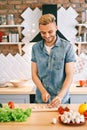 Smiling young man cooking healthy food in the kitchen at home. Royalty Free Stock Photo