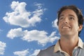 Smiling young man daydreaming against cloudy sky Royalty Free Stock Photo