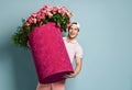 Portrait of happy smiling man shorts and cap delivery guy holding huge pink box with flowers roses for birthday, meeting