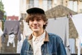 Smiling young man in denim jacket standing in front of hanging laundry Royalty Free Stock Photo