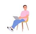 Smiling young man freelancer cartoon character sitting on chair and working online using laptop Royalty Free Stock Photo