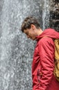 Smiling young man in front of a waterfall