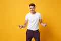 Smiling young man guy 20s in white t-shirt posing isolated on yellow orange background in studio. People sincere Royalty Free Stock Photo