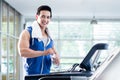 Smiling young man on treadmill holding water bottle Royalty Free Stock Photo