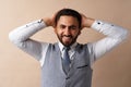 Smiling young man with hands behind head against beige background Royalty Free Stock Photo