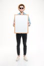 Smiling young man in hat and sunglasses holding blank whiteboard Royalty Free Stock Photo