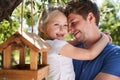 Joyful father and daughter hugging by the tree with bird feeder