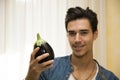 Smiling young man holding a fresh eggplant Royalty Free Stock Photo