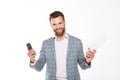 Smiling young man holding gazette and mobile phone. Royalty Free Stock Photo