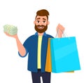 Smiling young man holding shopping bags. Person showing bunch of cash, money, currency notes in hand. Modern lifestyle, digital. Royalty Free Stock Photo