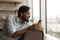 Smiling mixed race young man with cellphone feeling dreamy. Royalty Free Stock Photo