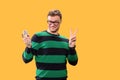 Smiling young man holds a microphone in his hand and showing a Peace sign on a yeloow background. Studio photo