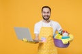 Smiling young man househusband in apron rubber gloves hold basin with detergent bottles washing cleansers doing Royalty Free Stock Photo