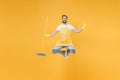 Smiling young man househusband in apron rubber gloves hold broom while doing housework isolated on yellow background