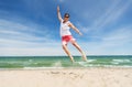 Smiling young man jumping on summer beach Royalty Free Stock Photo