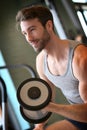 Smiling young man lifting weights in a fitness club Royalty Free Stock Photo