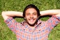 Smiling young man lying in grass listening to music Royalty Free Stock Photo