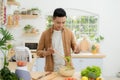 Smiling young man making vegetables salad in the kitchen at home