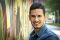 Smiling young man next to colorful graffiti wall Royalty Free Stock Photo